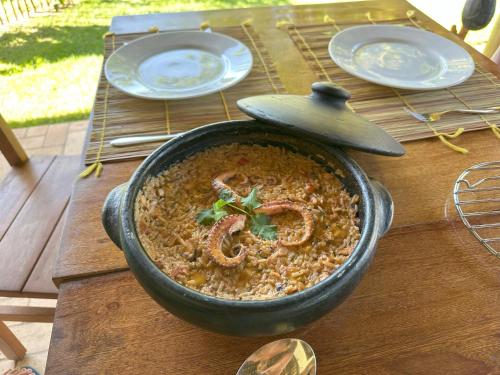 a bowl of food on a wooden table with plates at Vila Sol Chalés in Pôrto de Pedras
