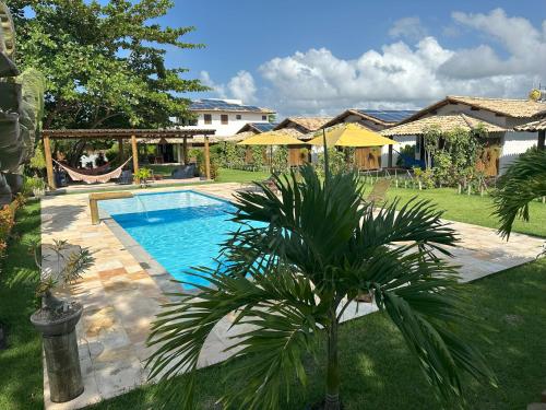 a swimming pool with a palm tree in a yard at Vila Sol Chalés in Pôrto de Pedras