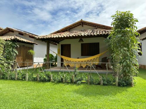 a house with a hammock in the yard at Vila Sol Chalés in Pôrto de Pedras