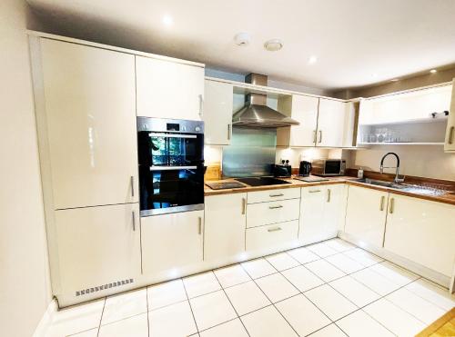 a white kitchen with white cabinets and appliances at Travaal.©om - 2 Bed Apartment Farnborough in Farnborough