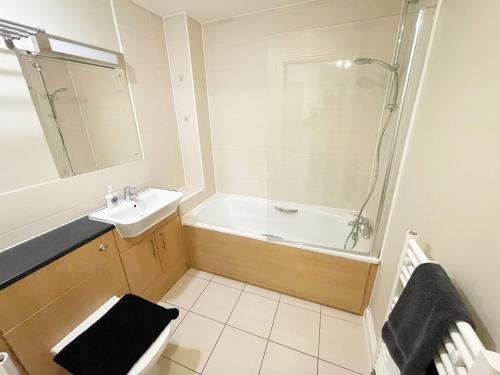 Travaal.©om - 2 Bed Apartment Farnborough في فارنبورو: حمام مع حوض ومغسلة ودش