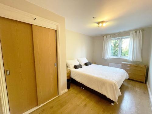 Schlafzimmer mit einem Bett und einem Fenster in der Unterkunft Travaal.©om - 2 Bed Apartment Farnborough in Farnborough