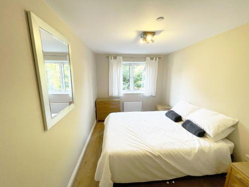 a bedroom with a white bed and two windows at Travaal.©om - 2 Bed Apartment Farnborough in Farnborough