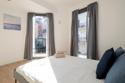 ein Schlafzimmer mit einem Bett und zwei großen Fenstern in der Unterkunft CENTRIC APARTMENT CAMP NOU 2 in Hospitalet de Llobregat