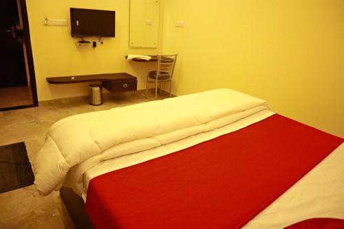 een bed in een kamer met een bureau en een televisie bij evergreen family homesty in Agra
