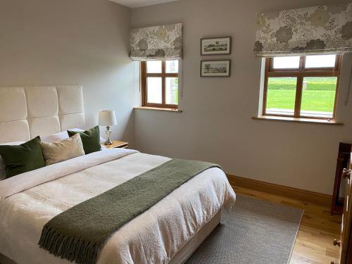 a bedroom with a large bed and two windows at Lissadell Lodge in Carney