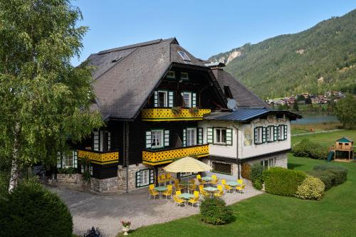 a large house with yellow tables and chairs in front of it at Hotel Harrida in Weissensee