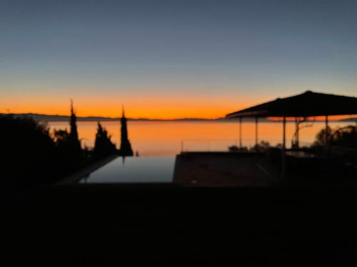 una puesta de sol sobre un cuerpo de agua con una piscina en VILLA LOVRAN - 150m to the beach - infinity pool - incredible sea view - Fitnessraum, en Lovran