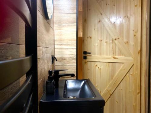 a bathroom with a sink and a wooden door at Apartamenty Leśna Przystań 2 in Węgorzewo