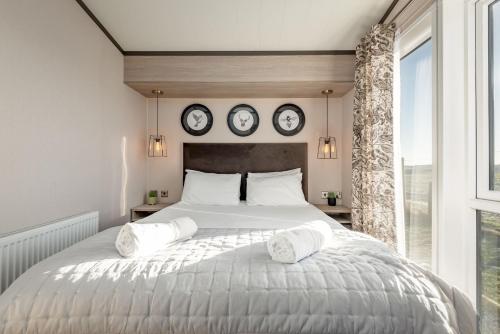 a bedroom with a large bed with three clocks on the wall at Lodge No 9 - St Andrews Lodge Park in Strathkinness