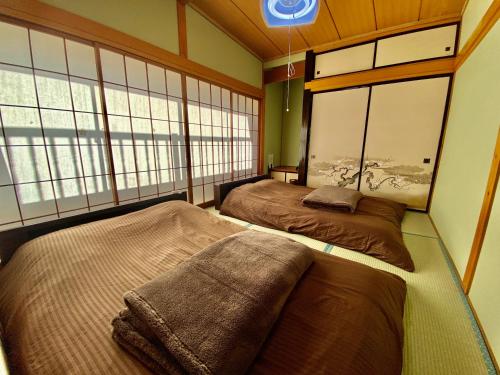 two beds in a room with two windows at 貸切御宿　憩（Ikoi）/ Nikko Kinugawa Area in Imaichi