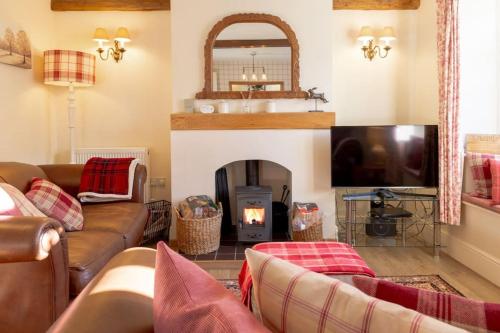 sala de estar con sofá y chimenea en Jasmine Cottage - 2 Bedroom in Heart of Bourton! en Bourton on the Water