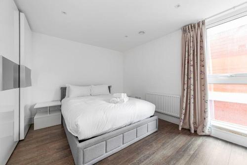 a white bedroom with a bed and a window at Charming & Large 1-Bedroom in the Heart of London in London