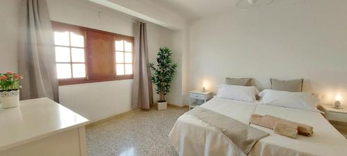 a white bedroom with a large bed and a window at Ten minutes from airport in Vecindario