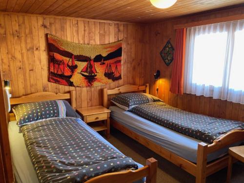 twee bedden in een kamer met houten wanden bij Chalet Alphütte in Rosswald