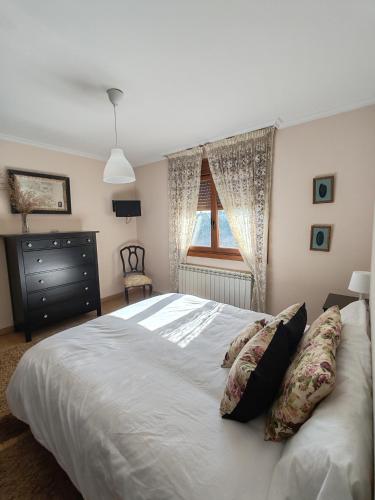 ein Schlafzimmer mit einem weißen Bett mit Kissen und einem Fenster in der Unterkunft A Mouta in Amoedo