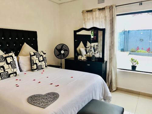 Schlafzimmer mit einem Bett mit einem Herzkissen und einem Spiegel in der Unterkunft Skyfly Bed & Breakfast in Manzini
