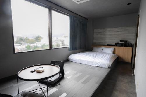 周南市的住宿－ピンポンホテル&キャビン pin pon hotel & cabin，酒店客房配有一张床、一张桌子和一张桌子以及椅子。