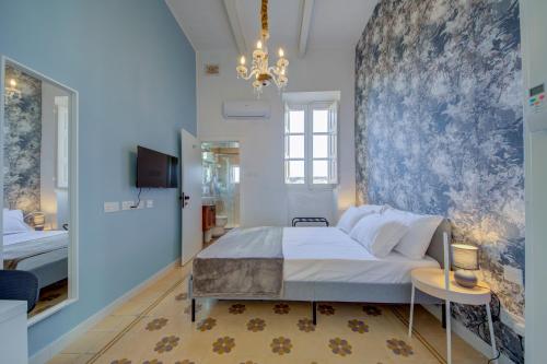 une chambre avec un grand lit et un lustre dans l'établissement Casa Marie, Stay in a Traditional Corner Townhouse in the 3 cities, built in 1881, à Cospicua