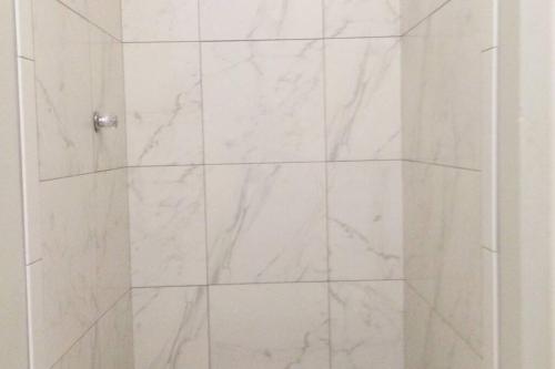 a white marble shower with a glass door at Tides Lobitos in Lobitos