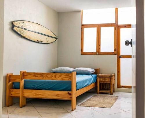 a bedroom with a bed with a surfboard on the wall at Tides Lobitos in Lobitos