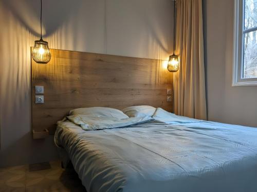 a bed in a bedroom with two lights on it at Cozy Tiny SolHouse 4 - Near Groningen in Kropswolde