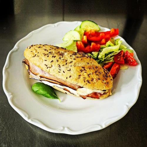 a white plate with a sandwich and vegetables on it at Kavárna a penzion REICHL in Králíky