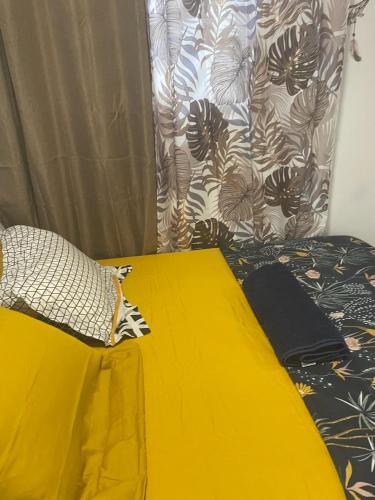 a bedroom with a yellow bed and a curtain at La sagesse in Cayenne