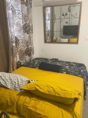 a bedroom with a yellow bed and a mirror at La sagesse in Cayenne