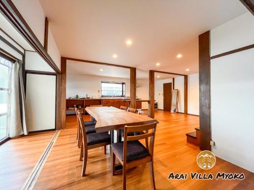 uma sala de jantar com uma mesa de madeira e cadeiras em Arai Villa Myoko em Myoko