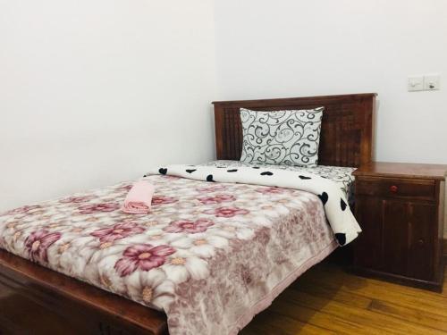 1 dormitorio con 1 cama con colcha de flores en Highest Village Bungalow, en Nuwara Eliya
