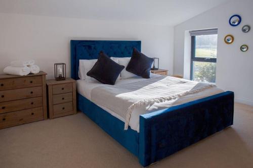 een slaapkamer met een blauw bed, een dressoir en een raam bij Discovery Barn - Luxury 2 Bed Barn Conversion! in Cropthorne