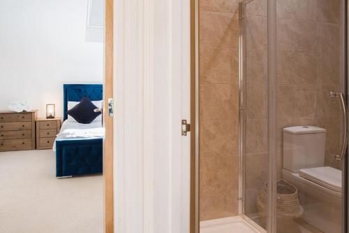 een badkamer met een douche, een toilet en een bed bij Discovery Barn - Luxury 2 Bed Barn Conversion! in Cropthorne