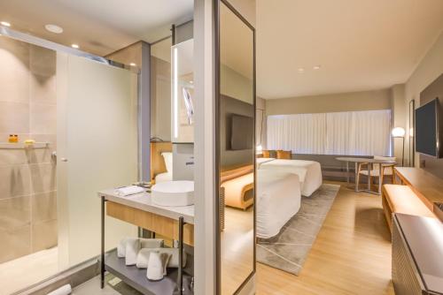 a hotel room with a bathroom and a bedroom at DoubleTree by Hilton Porto Alegre in Porto Alegre