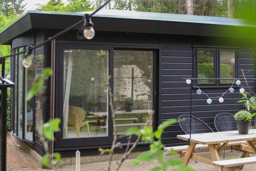 a black tiny house with a picnic table at Boshuisje op de Veluwe met sfeervolle tuinkas in Putten