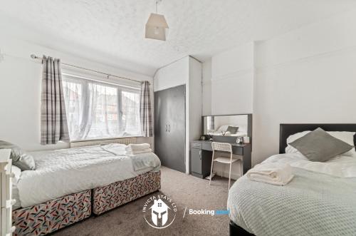 1 dormitorio con 2 camas, escritorio y ventana en 3 Bedroom House By Invicta Stays Short Lets Near City Centre Leicester With Free Wi-Fi Free Parking en Leicester