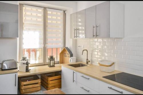 une cuisine avec des armoires blanches, un évier et une fenêtre dans l'établissement Au cœur d'AVIGNON 2 - WIFI - CENTRE VILLE, à Avignon