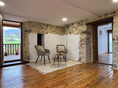 La Casina de Villar في Villar de Huergo: غرفة بجدار حجري مع كرسيين وطاولة