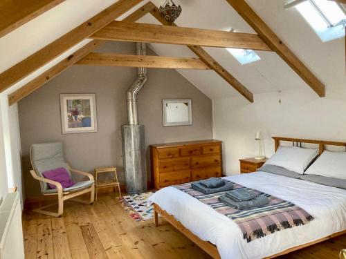 a bedroom with a large bed and a chair at Barn conversion in Zennor in St Ives