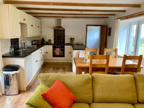 a living room with a green couch and a kitchen at Barn conversion in Zennor in St Ives