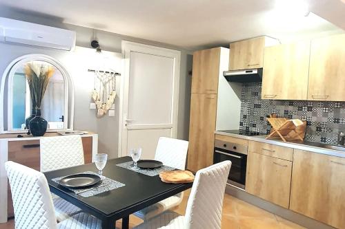 a kitchen with a table with chairs and a tableasteryasteryasteryasteryasteryastery at Les Oliviers : Studio spacieux belle vue mer, Clim in Port-Vendres