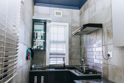 uma cozinha com um lavatório e uma janela em New England Guest House by Ilawu em Pietermaritzburg