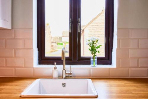 a white sink in a kitchen with a window at Bluebirds Cottage - Light & Airy 2 Bed in Bourton! in Bourton on the Water