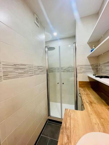 La salle de bains est pourvue d'une douche en verre et d'un comptoir en bois. dans l'établissement Vue mer à La Baule : Le Victor Hugo, à La Baule