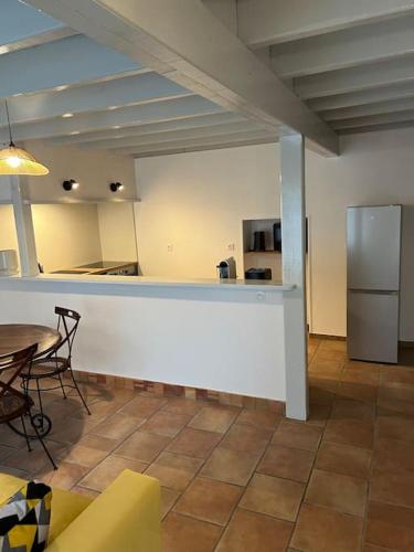 a kitchen with a counter and a table and a refrigerator at Charmante maison en Brenne in Vendoeuvres