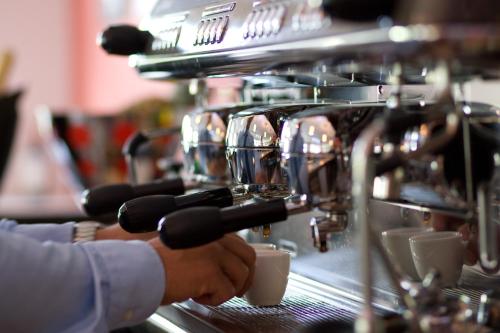 eine Person macht Kaffee in einer Espressomaschine in der Unterkunft Hotel La Baia in Cochem