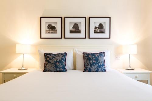 a bedroom with a white bed with three pictures on the wall at Abbey Fields By Chef & Brewer Collection in Kenilworth