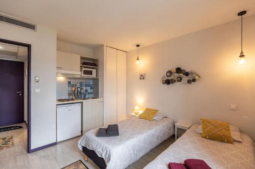 une petite chambre avec deux lits et une cuisine dans l'établissement Tithome 1 - Gare, centre ville, vue montagne et château, à Lourdes