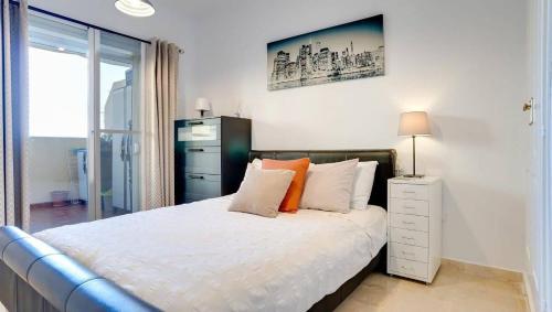 une chambre avec un lit avec des draps blancs et des oreillers orange dans l'établissement Lovely Aldea Beach Apartment, à Manilva