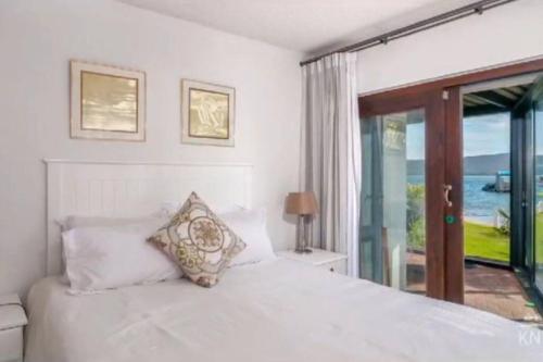 a bedroom with a white bed with a view of the ocean at Waterfront Apartment in Knysna